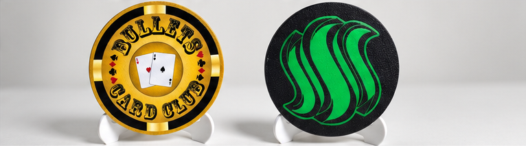 Bullets Card Club dealer button in gold and black beside a black button with green artwork, both on stands